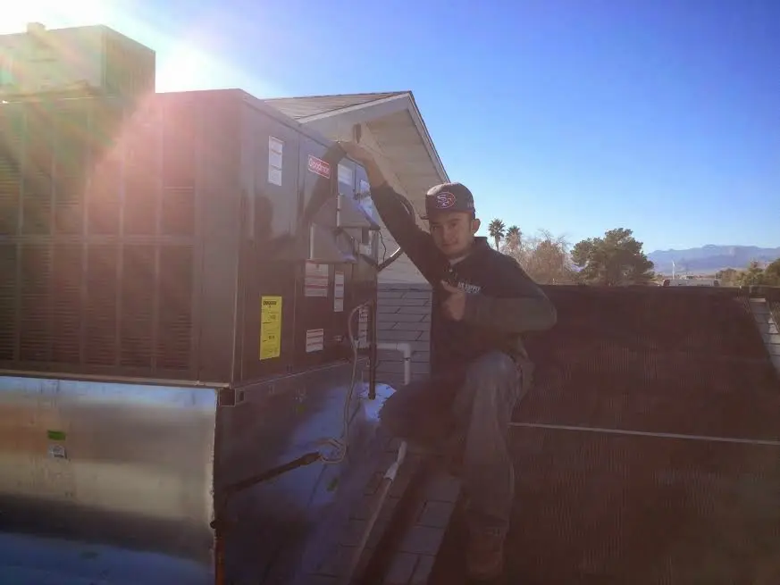 HVAC technician performing Air Duct Cleaning on a rooftop unit in Brecknock
