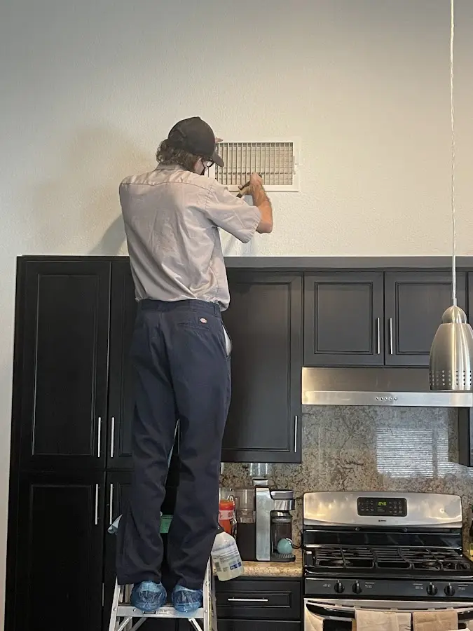 Technician inspecting an air vent during HVAC service in Brecknock